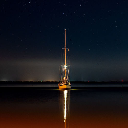 Sailboat in sea against sky at night
