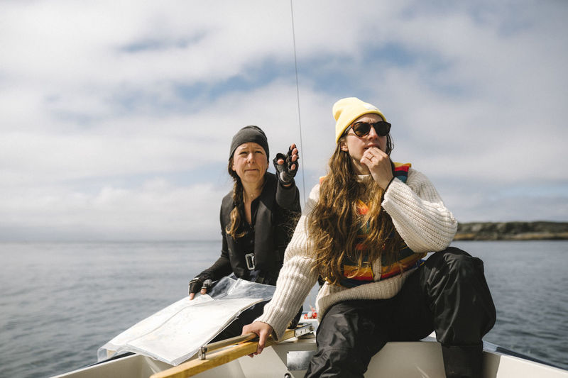 Women sitting on boat and using map to set direction