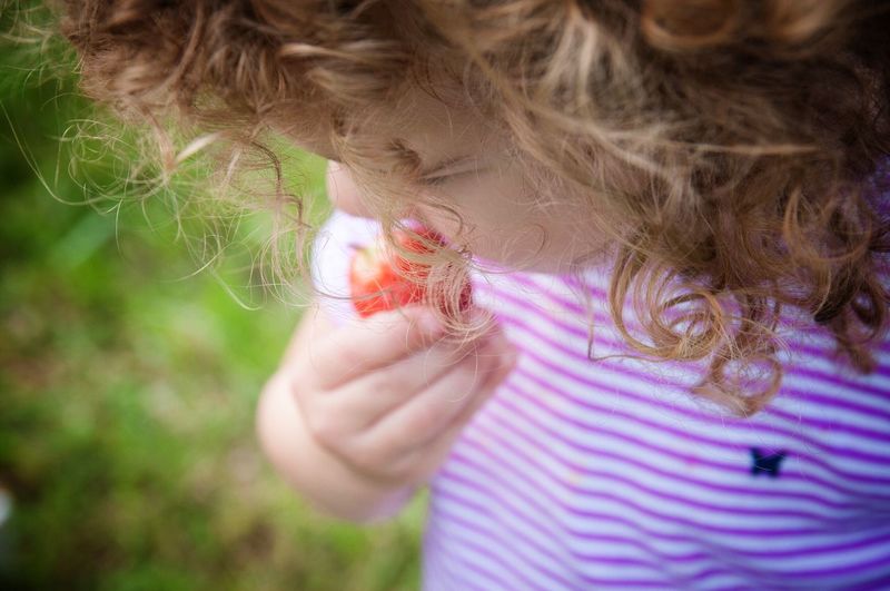 High angle view of girl eating strawberry