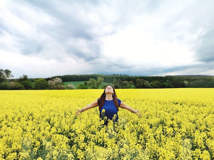 Woman with yellow flowers on field against sky