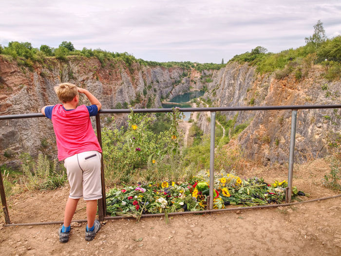 Boy stay at flowers on ground as memory to victims died at this place. flowers at old closed mine
