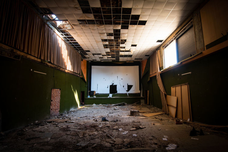 Abandoned and damaged interior of a stage theatre with bright light entering the building. 