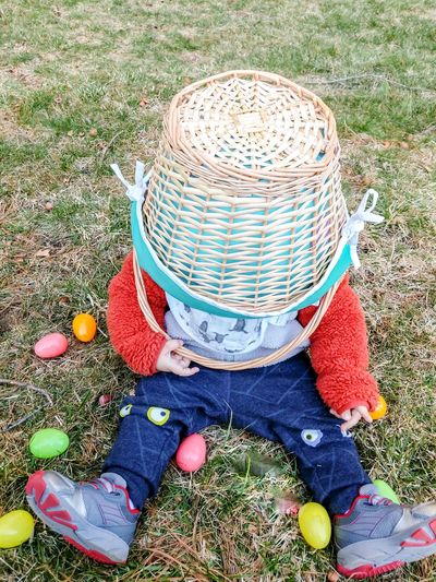 Child playing with easter basket while sitting on grass lawn