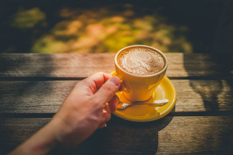 Cropped hand holding coffee on table