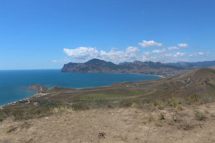 Scenic view of sea and mountains against blue sky