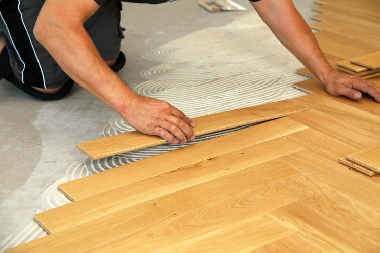 Cropped hands of carpenter placing planks on floor at home