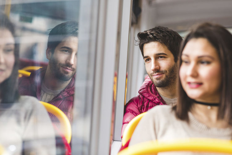 Uk, london, portrait of smiling young man in bus looking out of window