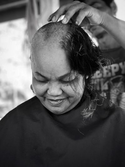 Man shaving woman head in barber shop