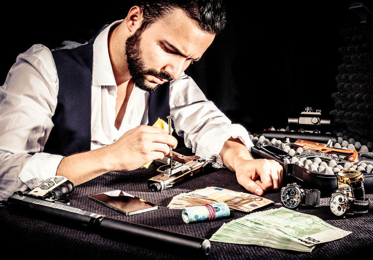 Young man repairing gun on table