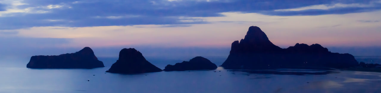 Panoramic view of rocks in sea against sky during sunset
