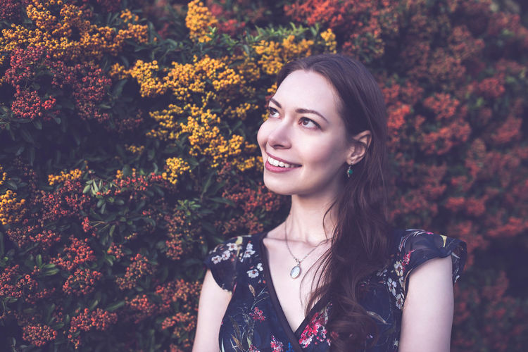 Portrait of young woman standing amidst yellow flowers