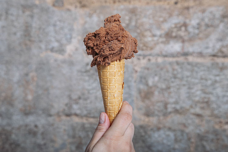 Hand holding chocolate ice cream cone. chocolate ice cream in waffle cone