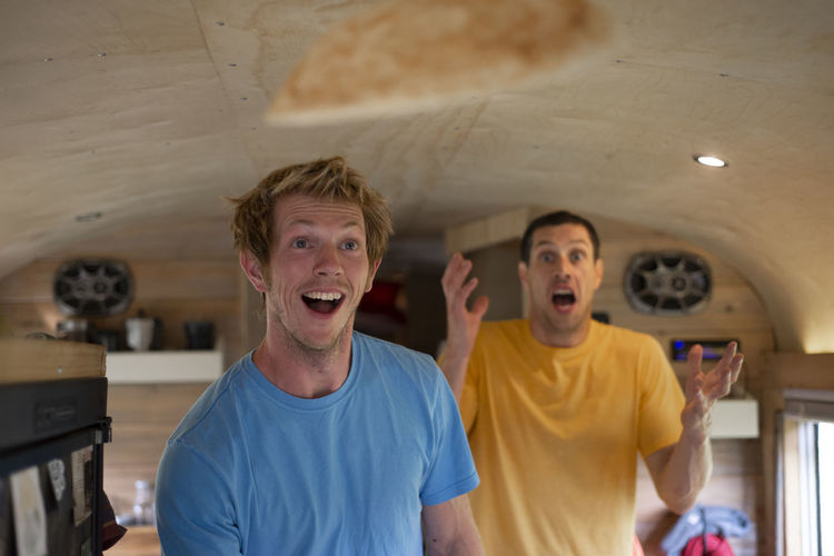 Two people making funny face while flipping crepes inside school bus