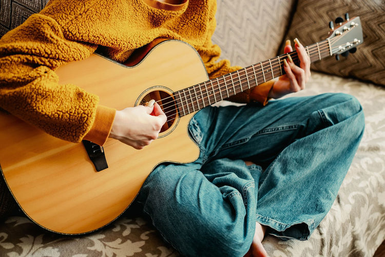 Woman sitting on sofa playing guitar