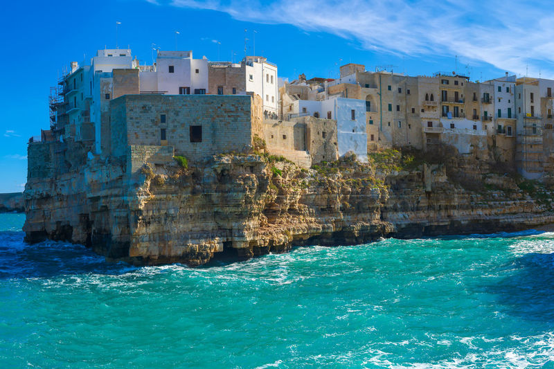 Buildings by sea against sky at polignano a mare