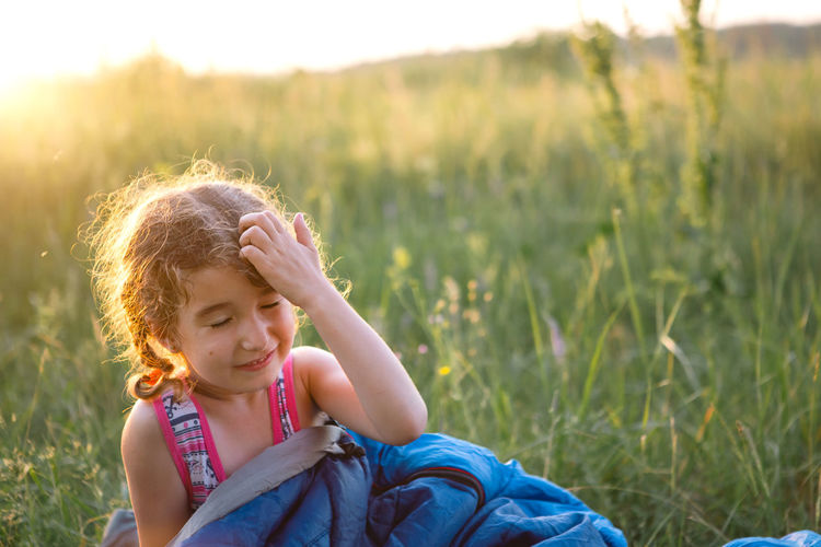Cute girl in sleeping bag in field