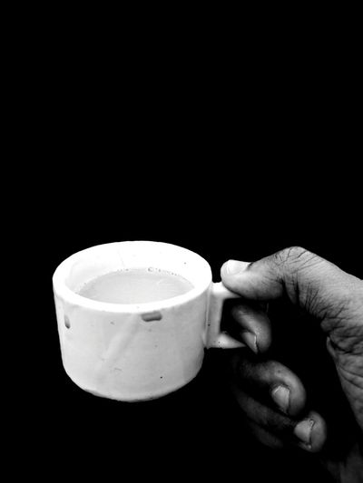 Man holding coffee cup against black background