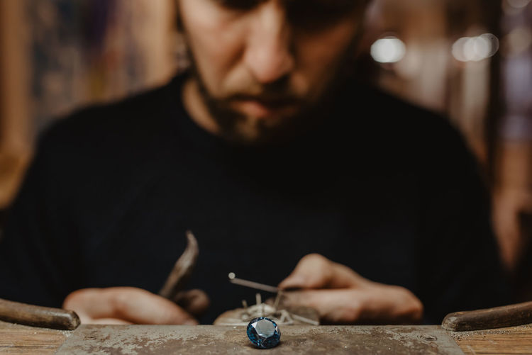 Jeweler holding unfinished ring in dirty hands and checking quality in workshop