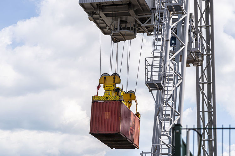 A container gantry crane on a rail loads the container into a barge standing on the banks of  river