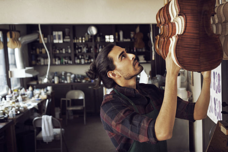 Worker hanging violin while standing in workshop