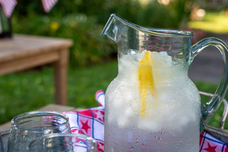Ice cold pitcher of water with lemon wedges on a tray in the backyard