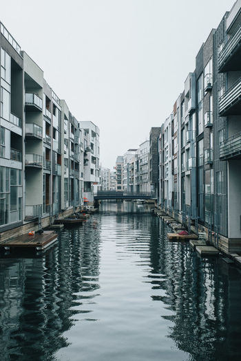 Canal amidst buildings in city against clear sky