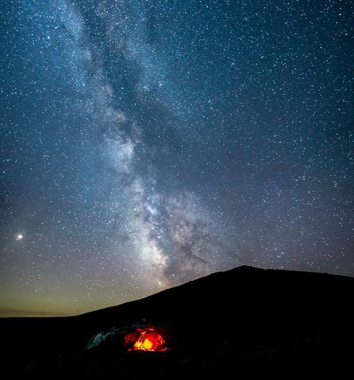 Bonfire on mountain against sky at night