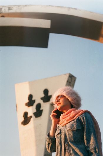 Low angel view of woman talking on phone against sky