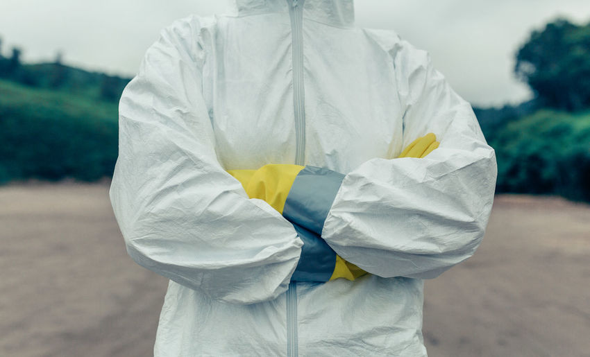 Midsection of doctor wearing protective workwear standing outdoors