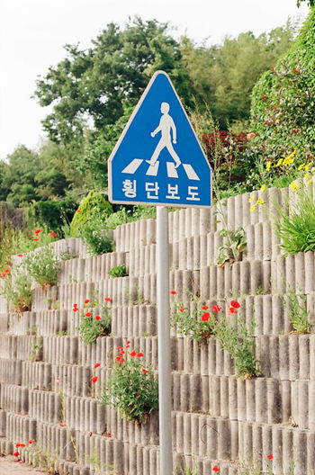 Information sign on road by fence against blue sky