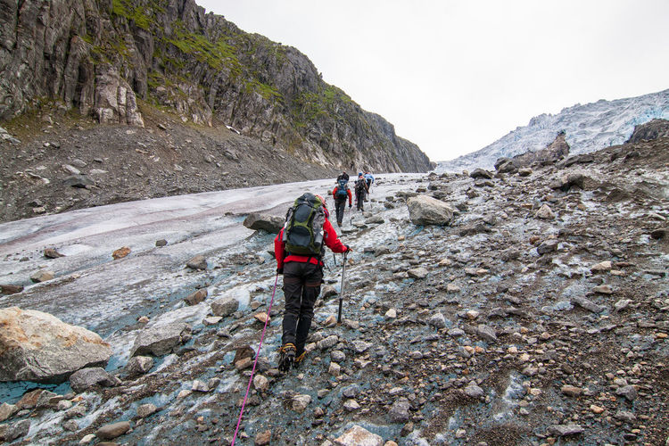 Rear view of people hiking on landscape against sky