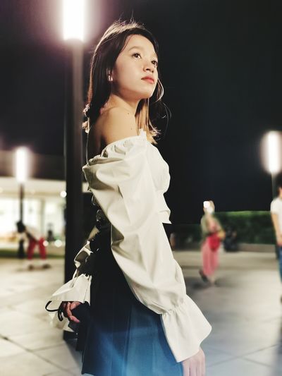 Beautiful young woman looking away at night