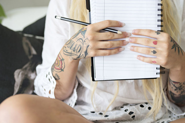 Woman with tattoos holding notebook, close-up