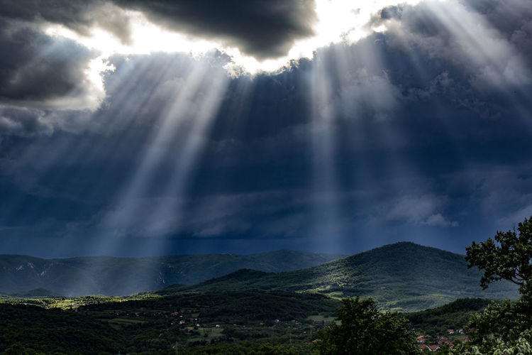 Sunlight streaming through clouds over mountains