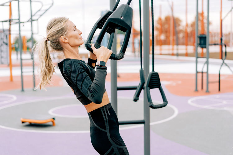 Strong athletic woman pulls up using equipment on the sports ground.