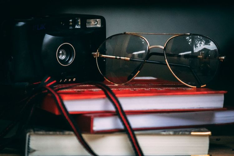 Close-up of sunglasses and camera on book