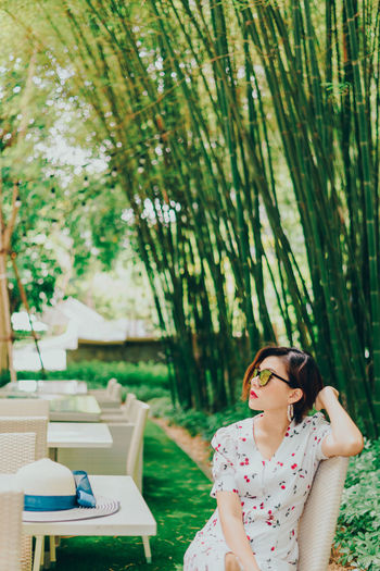 Woman standing by plants against trees
