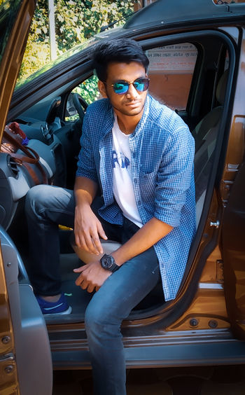 Young man wearing sunglasses sitting in car