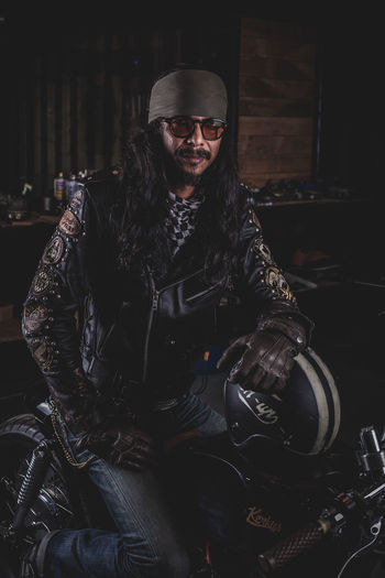 Portrait of fashionable motorcyclist sitting on motorcycle