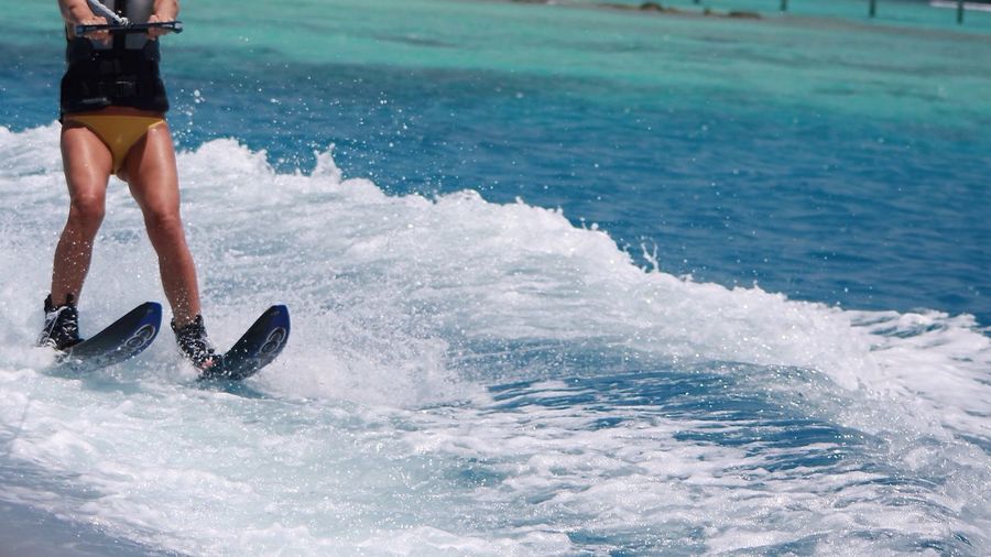 Low section of woman wakeboarding in sea