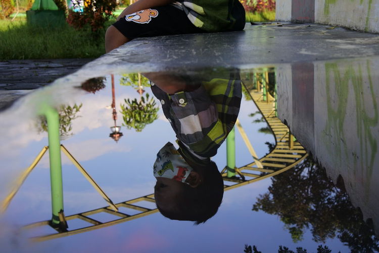 Low section of man reflection in water