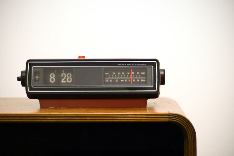 Close-up of old-fashioned radio with alarm clock on sideboard