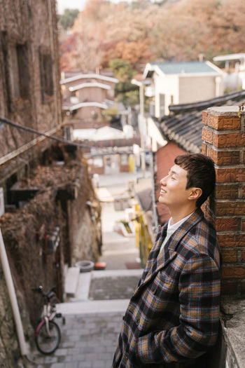 Side view of man standing on street against buildings in city
