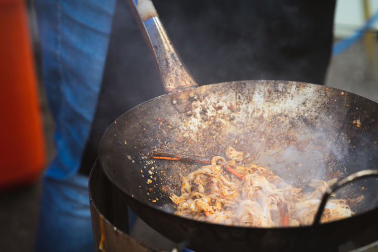 Cooking fried kue teow noodles in a wok at a local stall in asia.