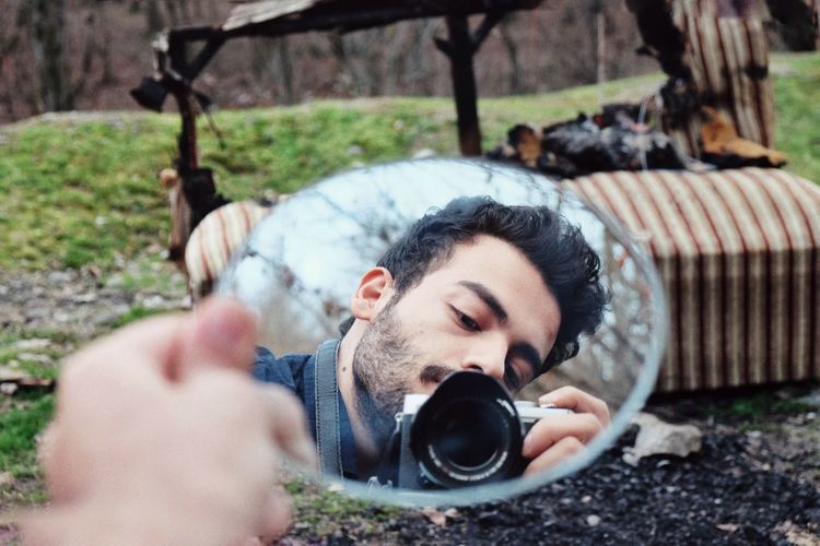 Reflection of teenage boy photographing outdoors