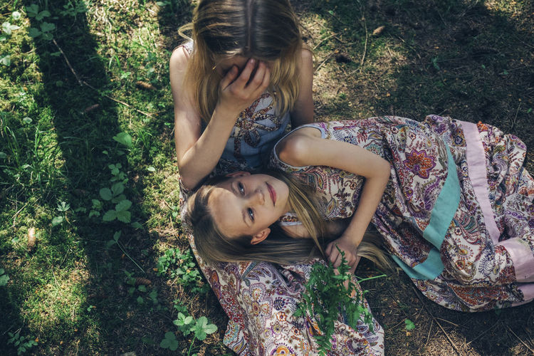 High angle view of girl lying on sister's lap in forest