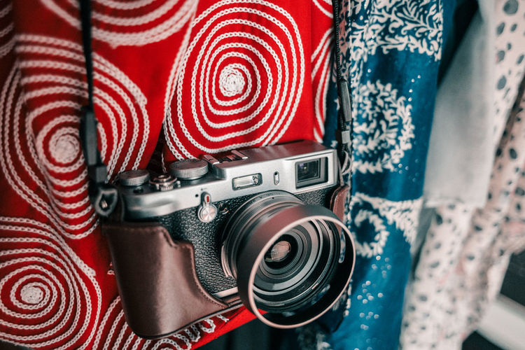 Close-up of old-fashioned camera hanging against clothes