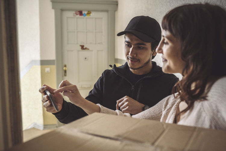 Female customer signing on mobile phone during package delivery