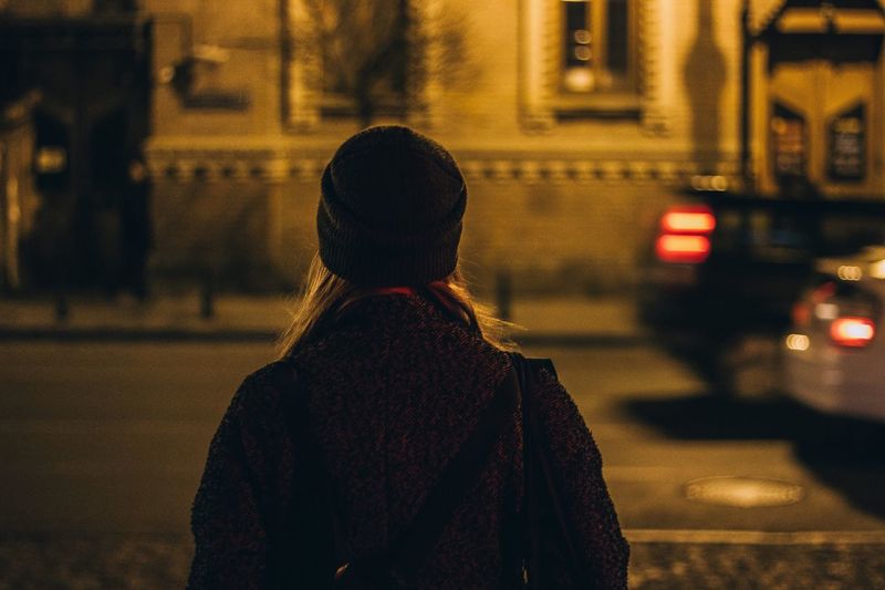 Rear view of woman standing on street at night