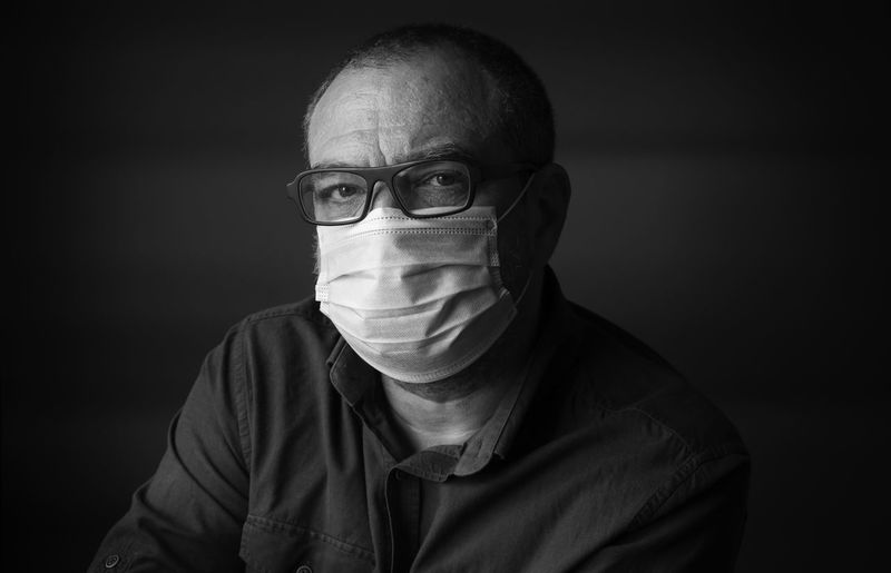 Man in medical protective mask in a dark room